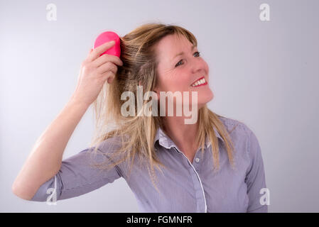 Portrait of a woman brushing her blond coloured hair Stock Photo