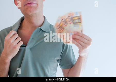 Man fanning himself with bank notes. Stock Photo