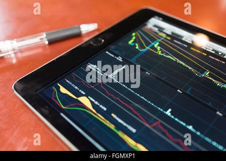 Tablet with stock graph on a wood table Stock Photo