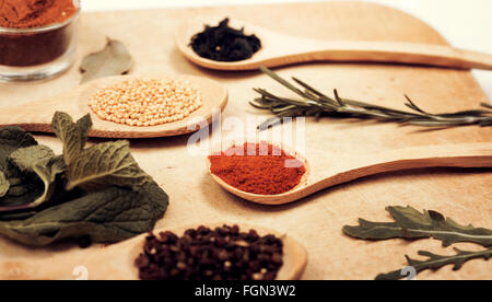 Various colorful spices on kitchen spoons over grunge wooden table Stock Photo
