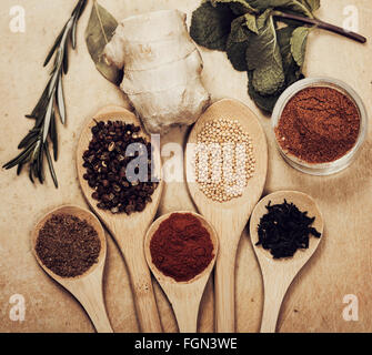 Various colorful spices on kitchen spoons over grunge wooden table Stock Photo