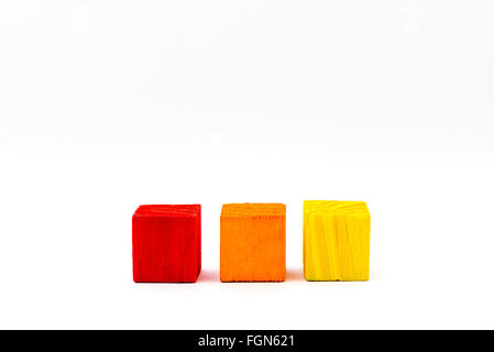Three toy wooden colored blocks isolated on white background, copy space available on the right Stock Photo
