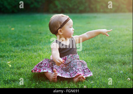 little girl sitting on green grass on the lawn Stock Photo