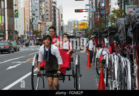 Tokyo Japan rickshaws with locals on street in Asakusa District on Kanon Street and traffic Stock Photo