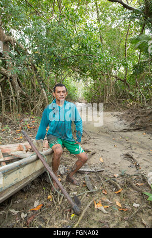 A local caboclo fisherman sitting on a dug out canoe, Marajo island [Ilha do Marajo] in a mangrove forest, the Brazilian Amazon Stock Photo