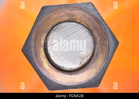 Closeup nut and bolt with selective focus on orange background Stock Photo