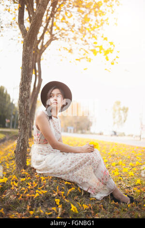 Asian pretty girl surrounded by the yellow flowers in summer . Stock Photo