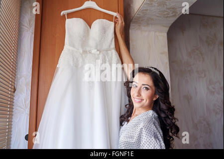 Beautiful bride in the morning of wedding day with her dress trying Stock Photo