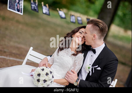 Happy bride and groom sitting on bench in the park Stock Photo