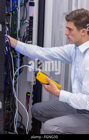 Serious technician using digital cable analyzer on server Stock Photo