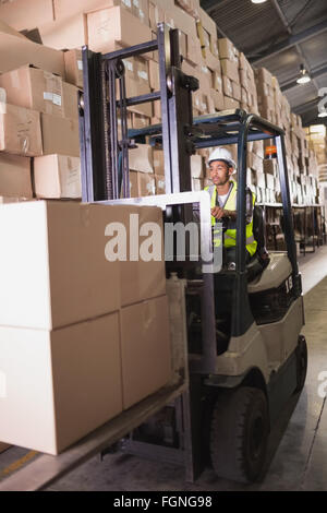 Worker operating forklift moving cardboard boxes near distribution ...