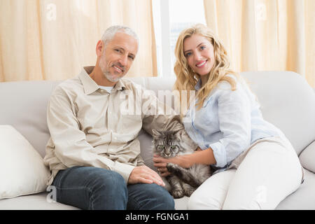 Happy couple with pet cat on sofa Stock Photo