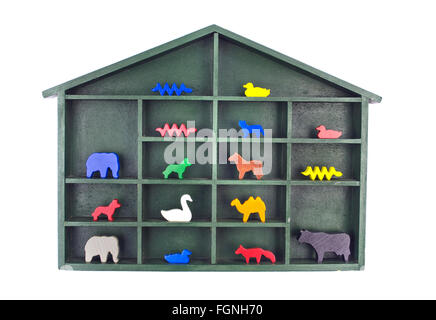 Green painted wooden shelf with a roof filled with various wooden animal toy figurines isolated on white Stock Photo