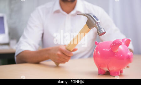 Man breaking piggy bank with hammer Stock Photo