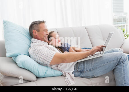 Father with daughter relaxing on the couch using laptop Stock Photo