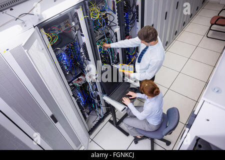 Team of technicians using digital cable analyser on servers Stock Photo