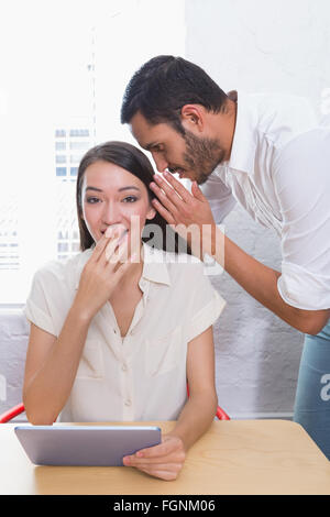 Man whispering into female friends ear Stock Photo