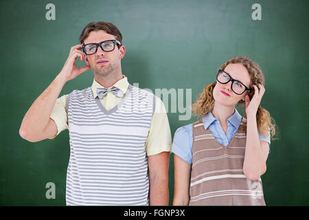 Composite image of geeky hipster couple thinking with hand on temple Stock Photo