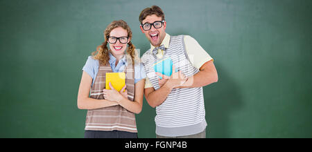 Composite image of geeky hipster couple holding books and smiling at camera Stock Photo