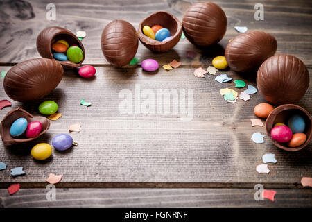 Delicious chocolate easter eggs and sweets on wooden background Stock Photo