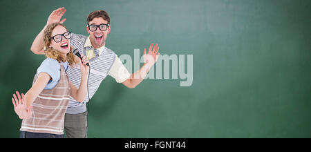 Composite image of geeky hipster couple singing into a microphone Stock Photo