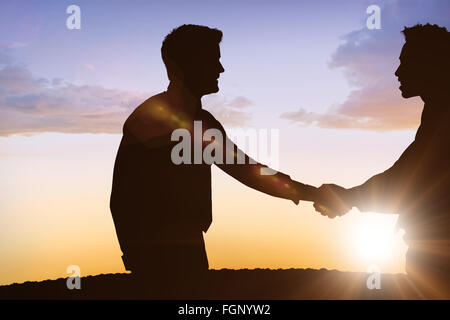 Composite image of silhouettes shaking hands Stock Photo