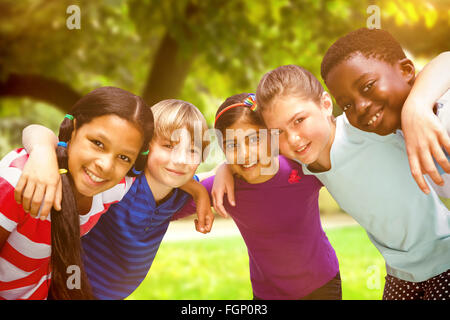 Composite image of happy children forming huddle at park Stock Photo
