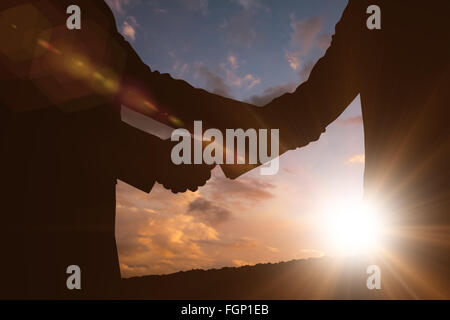 Composite image of silhouettes shaking hands Stock Photo