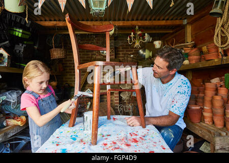 Father and daughter painting chair in workshop Stock Photo