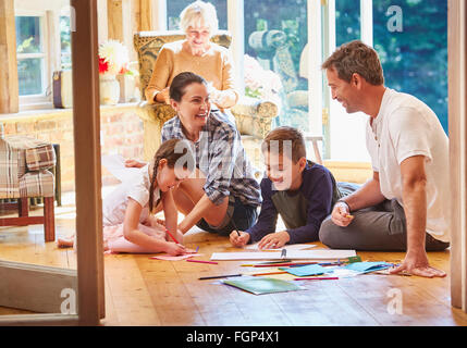 Family coloring on floor in sun room Stock Photo
