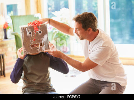 Father placing robot mask on son Stock Photo