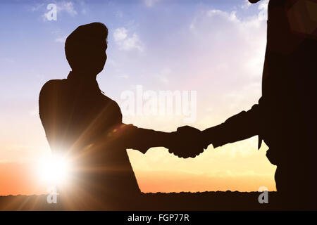 Composite image of silhouettes shaking hands Stock Photo