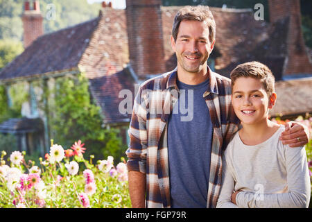 Portrait smiling father and son in sunny flower garden Stock Photo