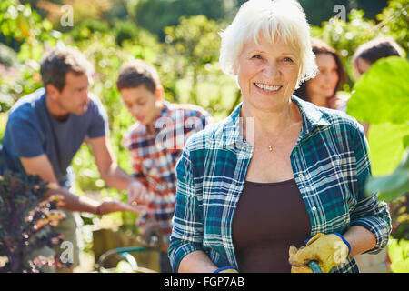 Portrait smiling senior woman in sunny garden with family Stock Photo