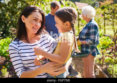 Affectionate mother holding daughter in sunny garden Stock Photo