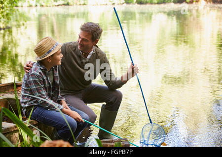 Father and son fishing with nets in pond Stock Photo