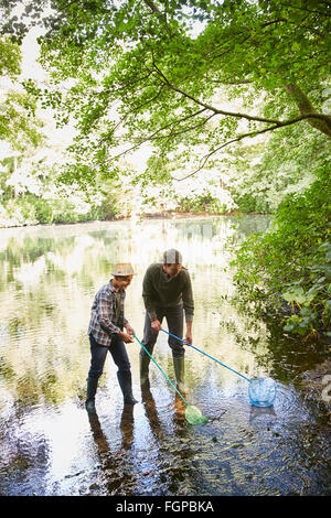 Father and son fishing with nets in pond Stock Photo