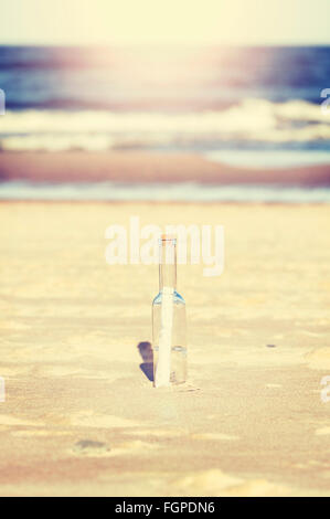 Vintage stylized message in a bottle on beach, shallow depth of field. Stock Photo
