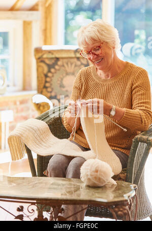 Smiling senior woman knitting scarf Stock Photo
