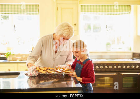 Grandmother and granddaughter baking gingerbread cookies in kitchen Stock Photo