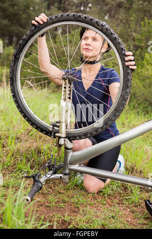 Athletic blonde checking her mountain bike Stock Photo - Alamy