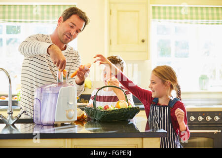 Family juicing vegetables in kitchen Stock Photo