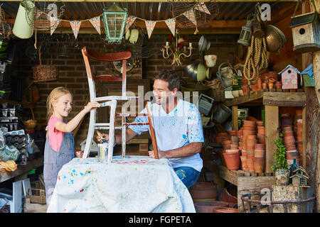 Father and daughter painting chair in workshop Stock Photo