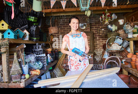 Portrait smiling woman with power sander in workshop Stock Photo