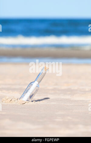 Message in a bottle on beach, shallow depth of field. Stock Photo
