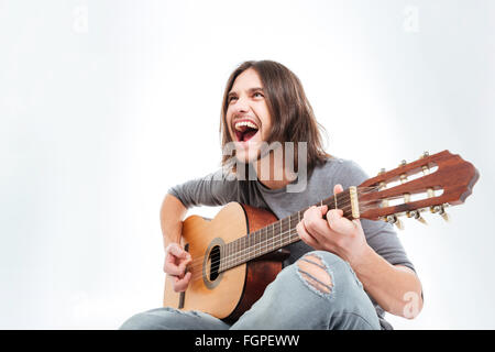 Happy young man with long hair playing guitar and singing over white background Stock Photo