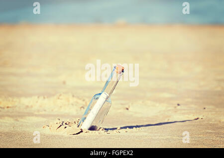 Retro toned message in a bottle on beach, shallow depth of field. Stock Photo