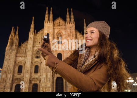 It is time to dress up and take a night tour in ultra-luxurious fashion expert - Milan, Italy. Smiling young woman with digital Stock Photo