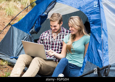 Young pretty hiker couple sitting in a tent looking at laptop Stock Photo