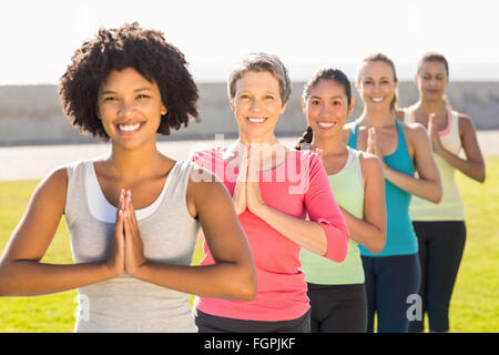 Smiling sporty women doing prayer position in yoga class Stock Photo